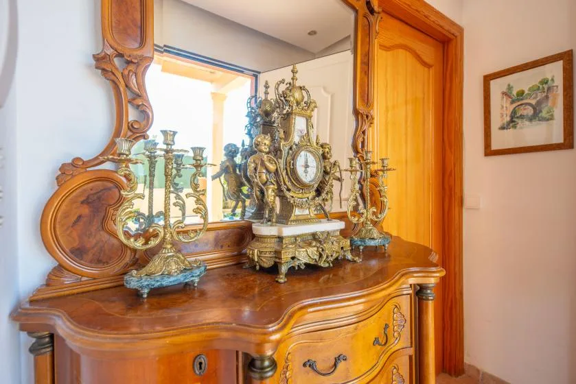An ornate wooden dresser with a decorative clock and candelabras stands beside a doorway.