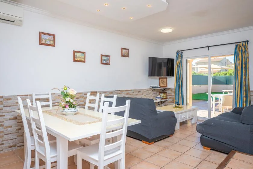 A dining and living area with a white table, seating, and patio doors.