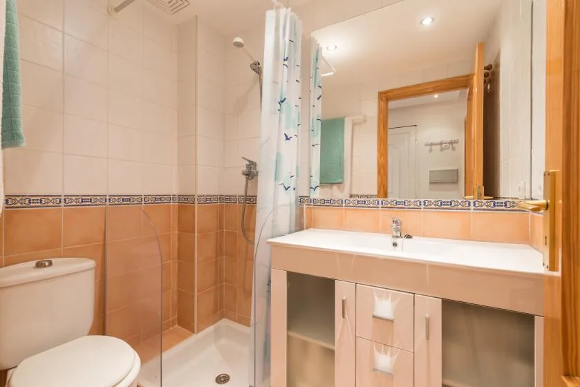 A tiled bathroom with a shower, toilet, and wide vanity.