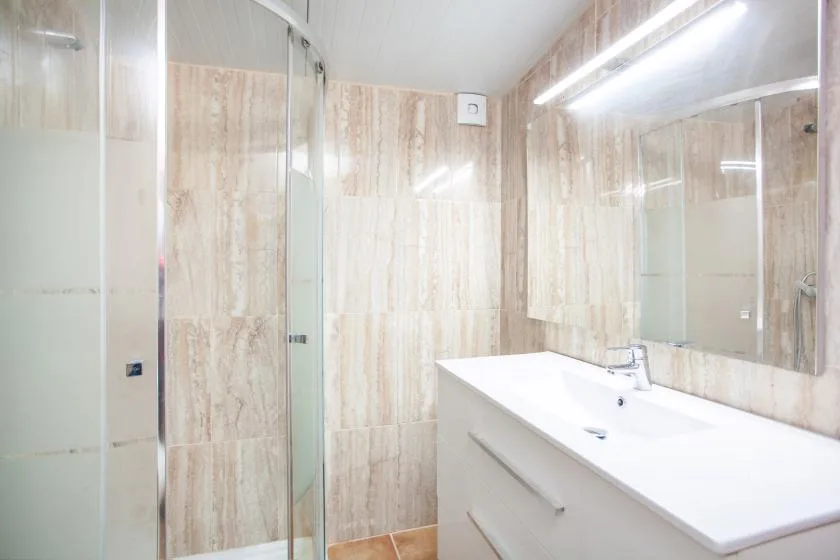 A bathroom with a glass shower and a wide sink counter.