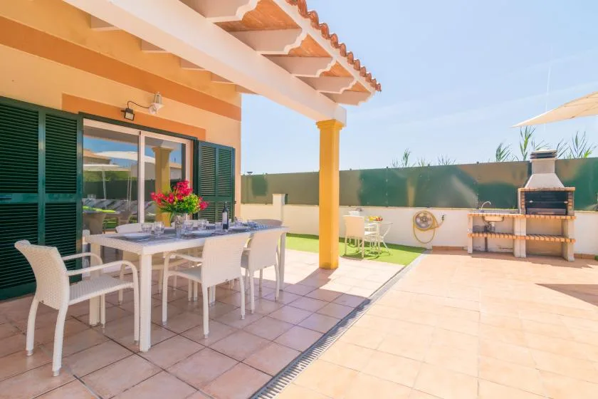 A covered outdoor dining area opens onto a sunny patio with a built-in grill.