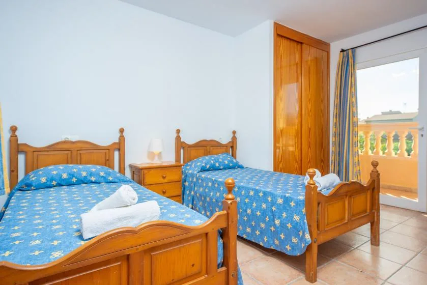 A bedroom with two wooden beds covered in blue patterned bedding.