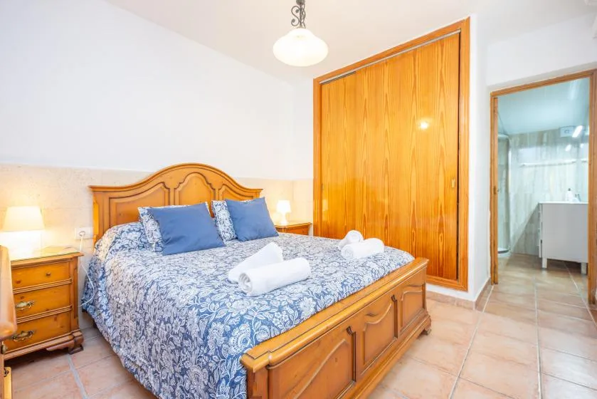 A bedroom with a wooden bed, blue patterned bedding, and an open doorway.