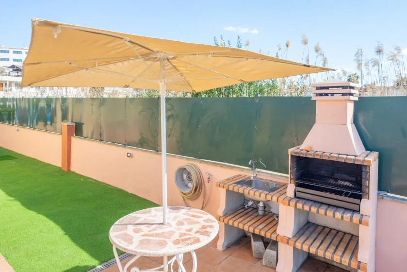 An outdoor patio with a barbecue grill, table, and large shade canopy.