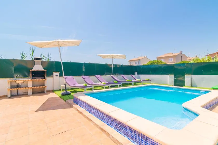 An outdoor swimming pool with lounge seating and umbrellas on a sunny patio.