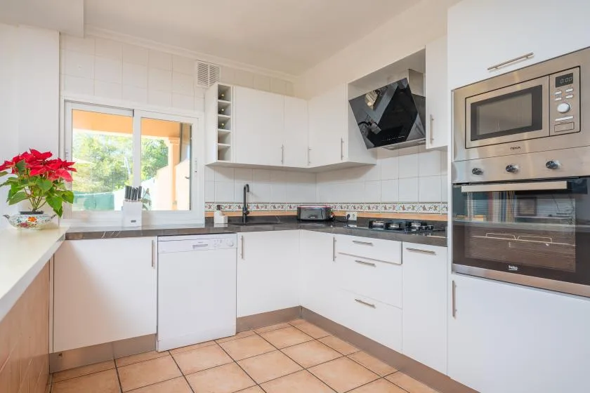 A bright kitchen with white cabinets, a tiled floor, and built-in appliances.
