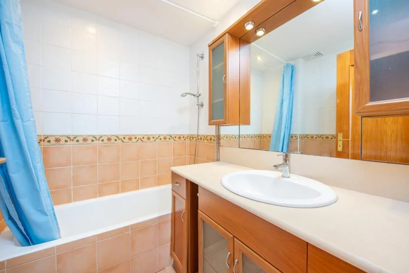A bathroom with a bathtub, blue shower curtain, and sink vanity.