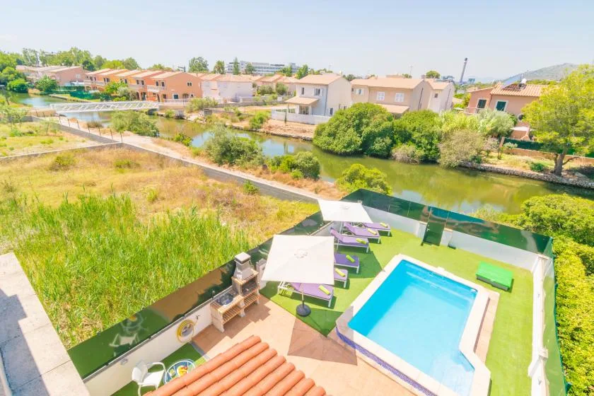 An outdoor pool area overlooks a canal, with lounge seating on the surrounding deck.