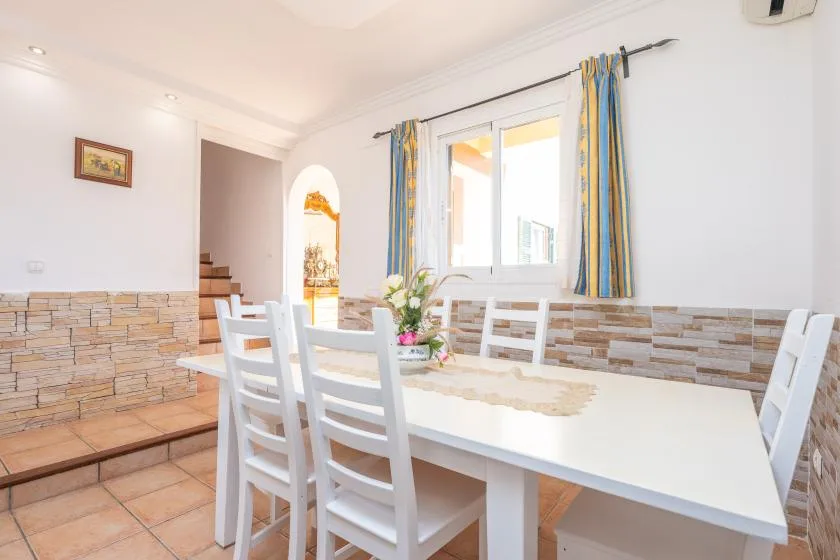 A bright dining area with a white table and chairs beside a window.