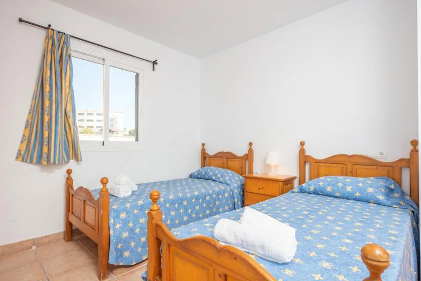 A bright bedroom with two wooden beds covered in blue patterned bedding.