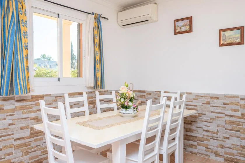 A dining area with a white table, chairs, and a flower arrangement.