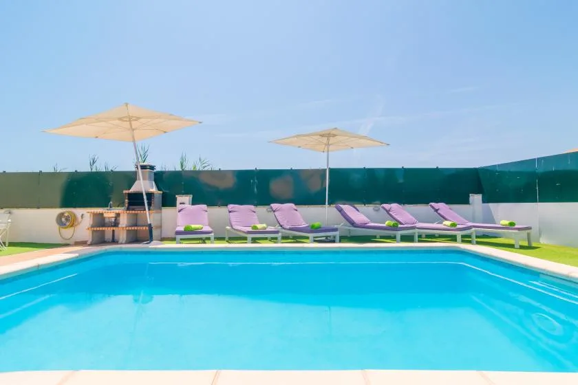 An outdoor swimming pool with lounge seating and sun umbrellas.