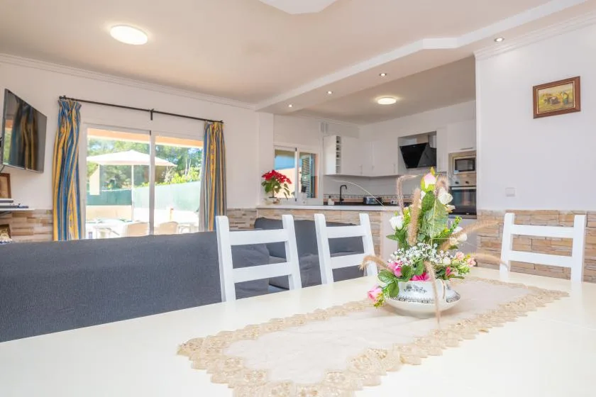 A dining area with a table and chairs opens onto a bright kitchen.