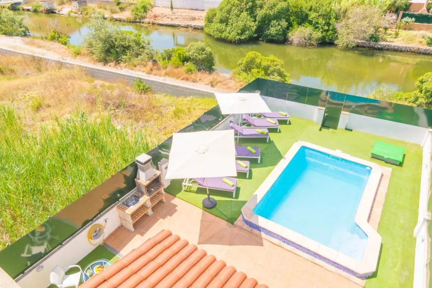 An outdoor pool area with lounge seating overlooks a river.