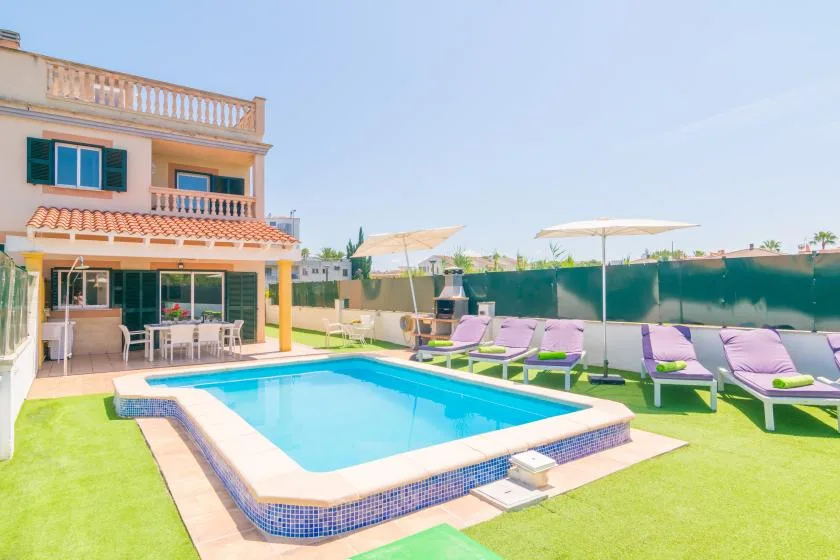 A swimming pool sits beside a patio with seating and sun loungers.
