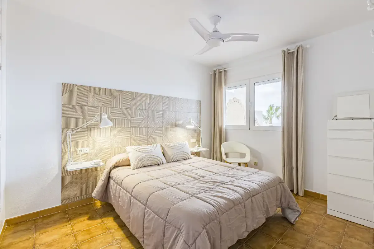 A bedroom with a double bed beneath a patterned wall panel.