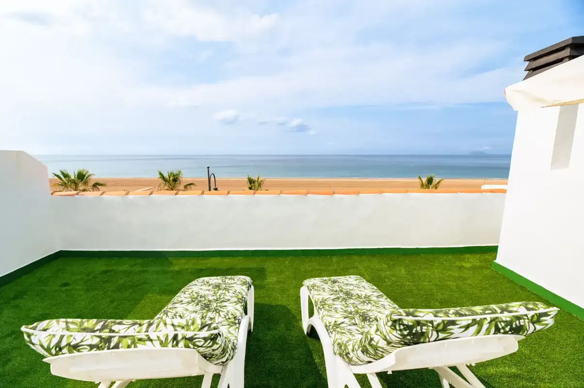 A terrace with lounge seating overlooks the beach and sea.