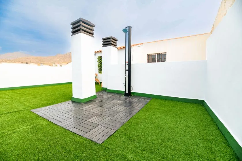 An outdoor shower area with a paved section surrounded by green lawn.