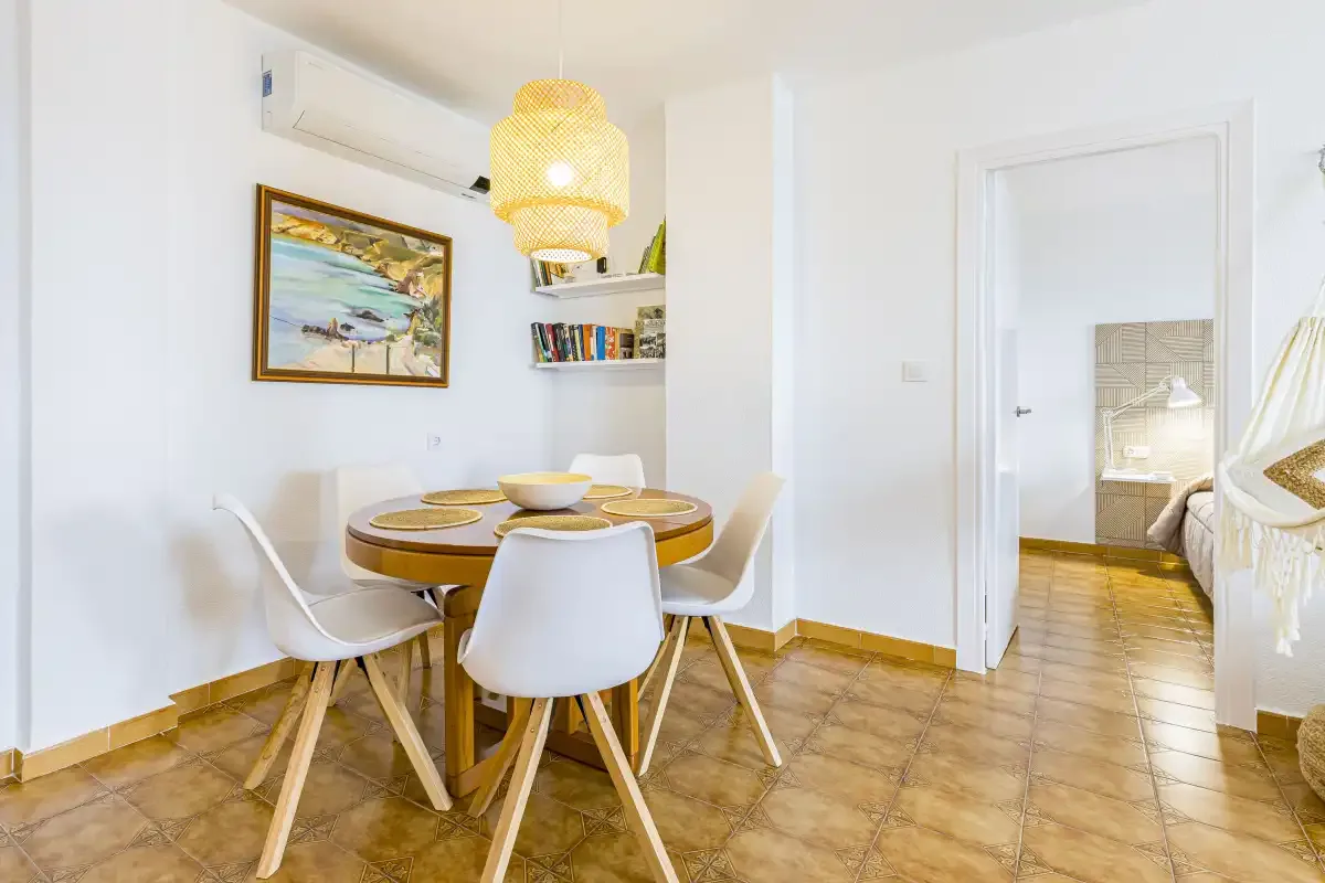 A dining area with a round table and several chairs beside an open doorway.