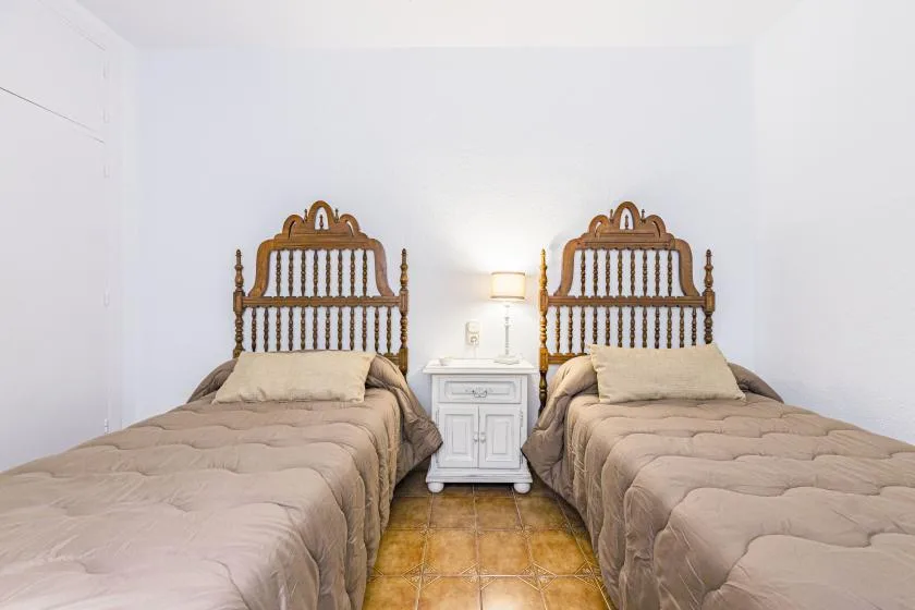 A bedroom with two beds separated by a small bedside table.