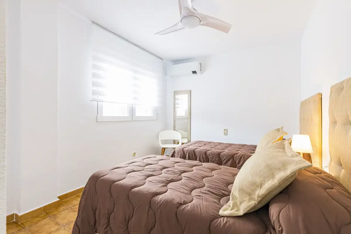 A bedroom with a large bed and a window with a light shade.