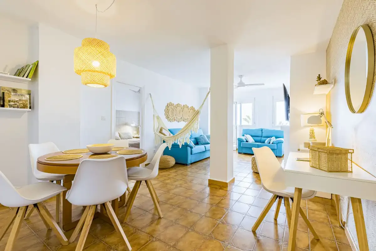 A bright living and dining area with a hammock and blue seating.