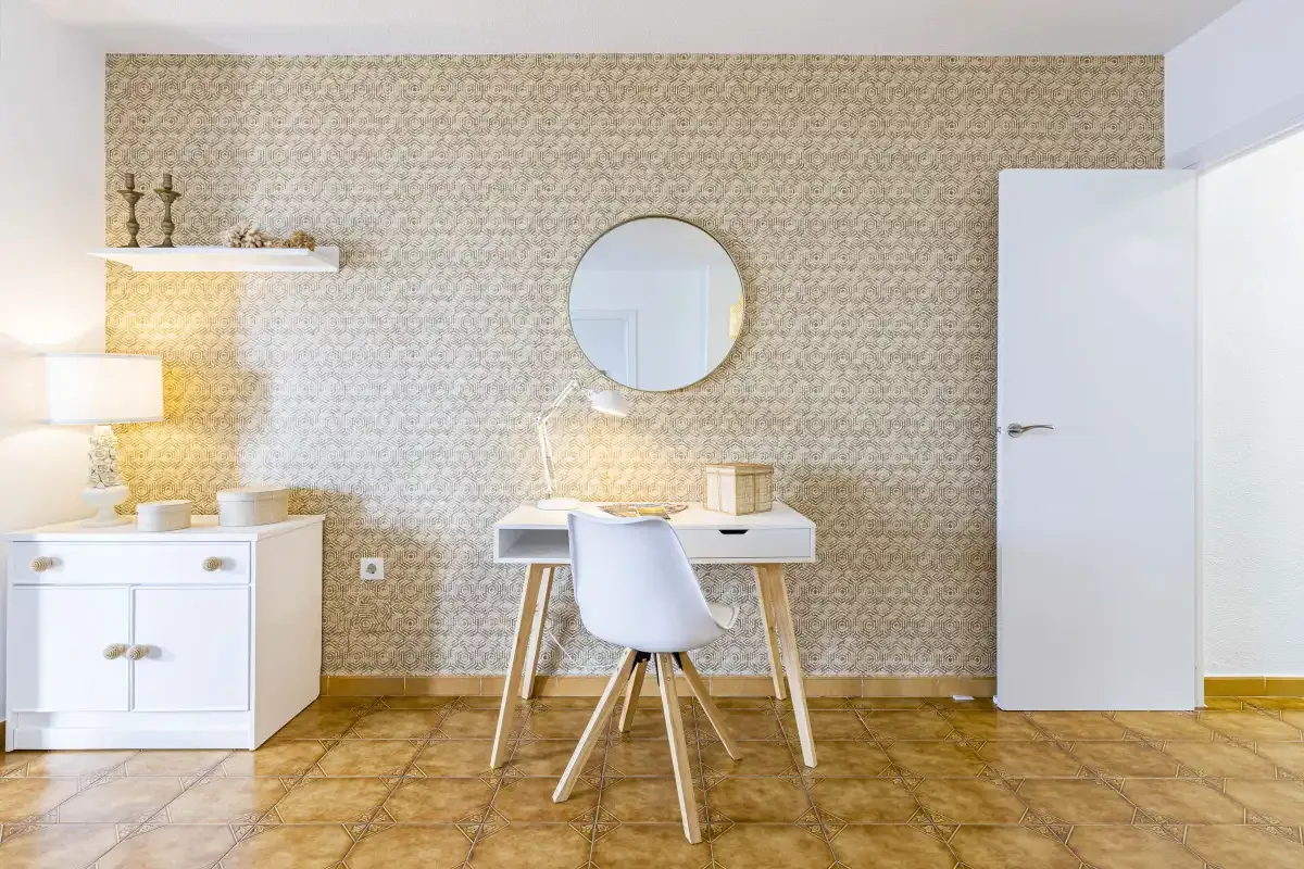 A bright room with a desk and chair against a patterned wall.