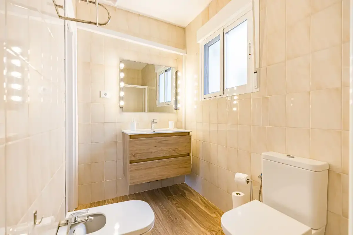 A tiled bathroom with a vanity, mirror, toilet, and shower.