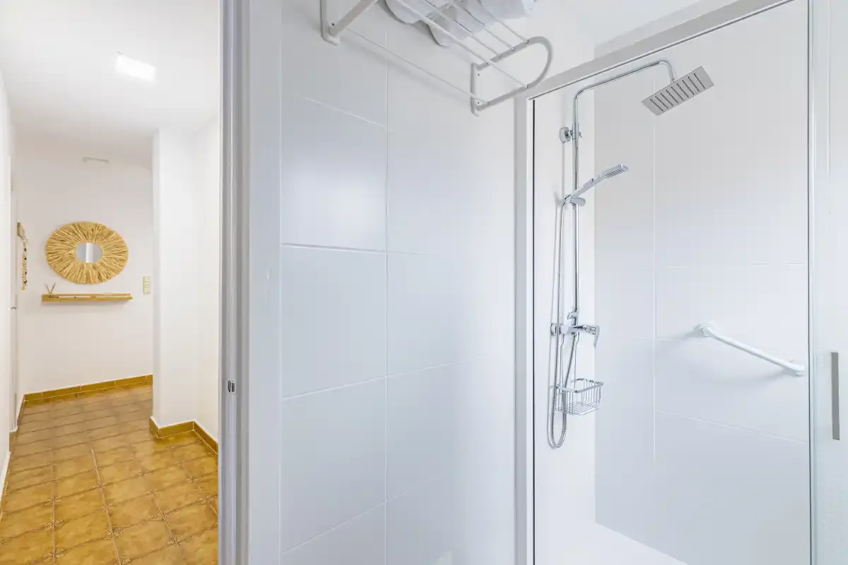 A tiled bathroom with a glass shower and chrome shower fixtures.