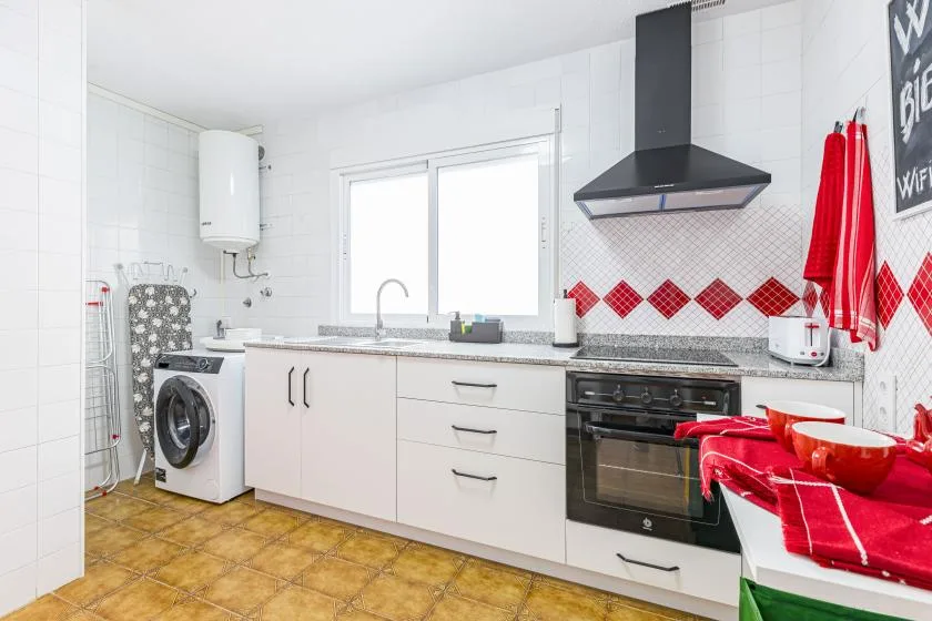 A bright kitchen with white cabinets, a window, and a black range hood.