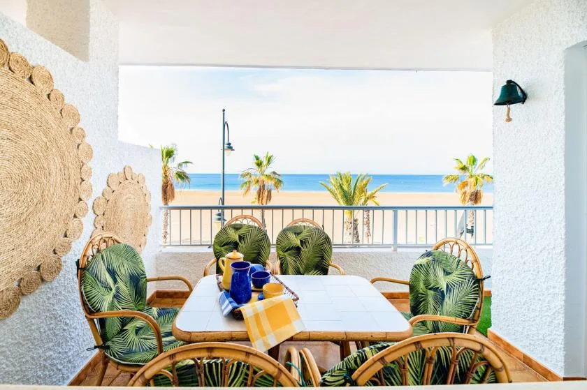 A balcony dining area overlooks palm trees and the ocean.