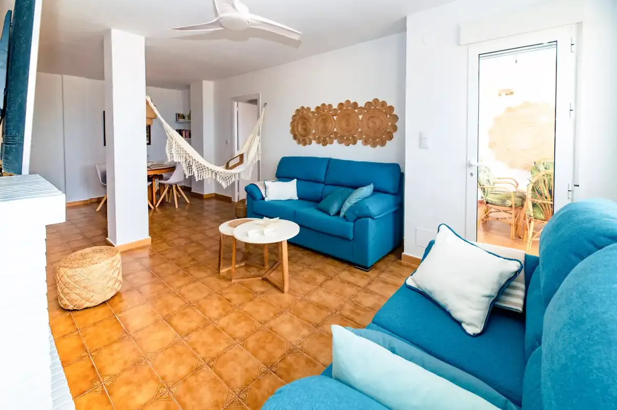 A living room with blue seating, a hammock, and a small coffee table.