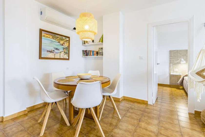 A dining area with a round table and white seating beside an open doorway.
