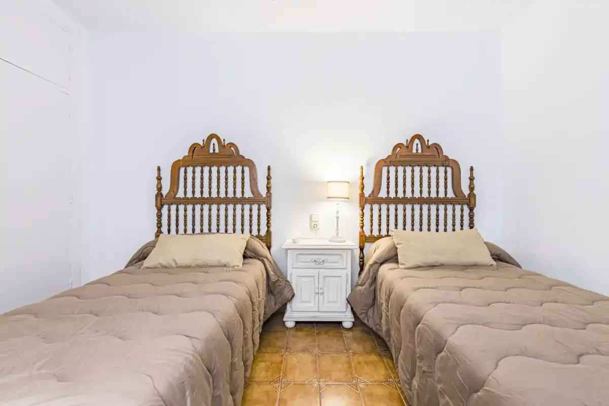 A bedroom with two beds and a small bedside table between them.