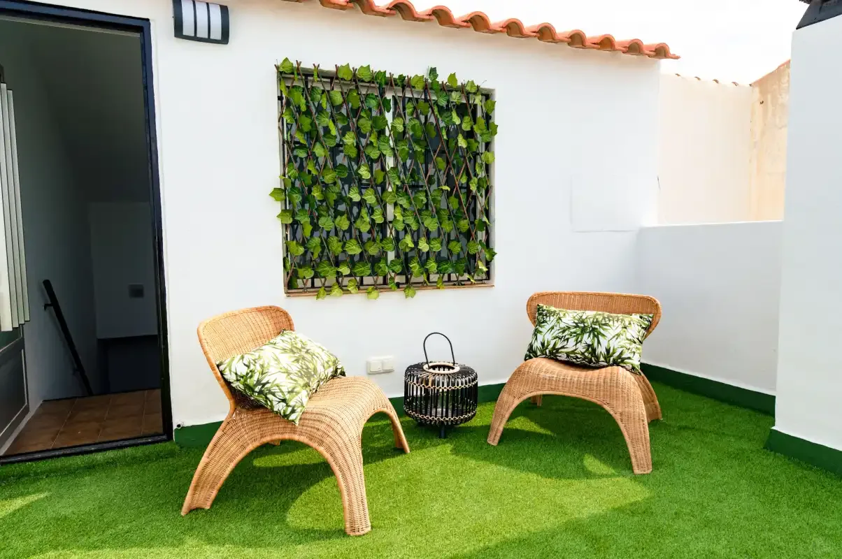 A small outdoor seating area with two woven chairs on green turf.