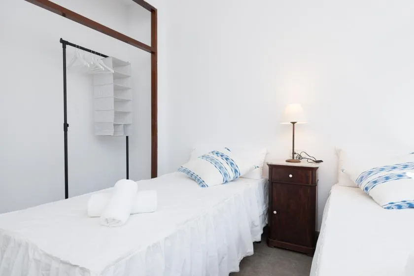 A bright bedroom with two beds and a small bedside table between them.