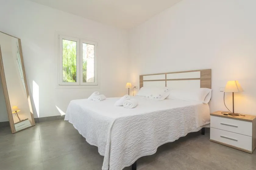 A bright bedroom with a large bed, bedside lamps, and a window.