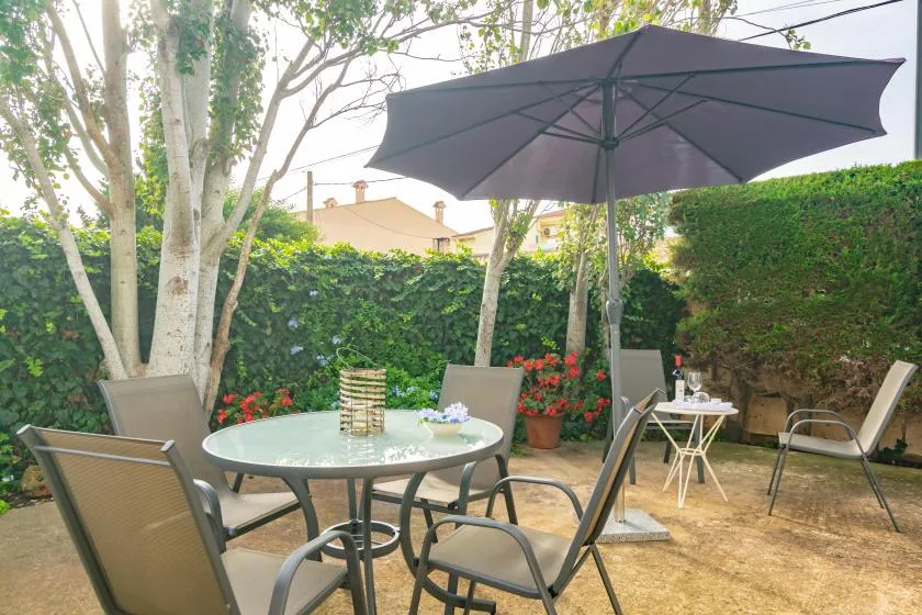 A garden patio with outdoor seating beneath a large umbrella.