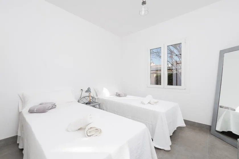 A bright treatment room with two massage tables and folded towels.