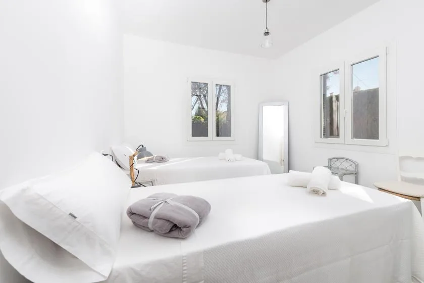A bright bedroom with white bedding and several beds.