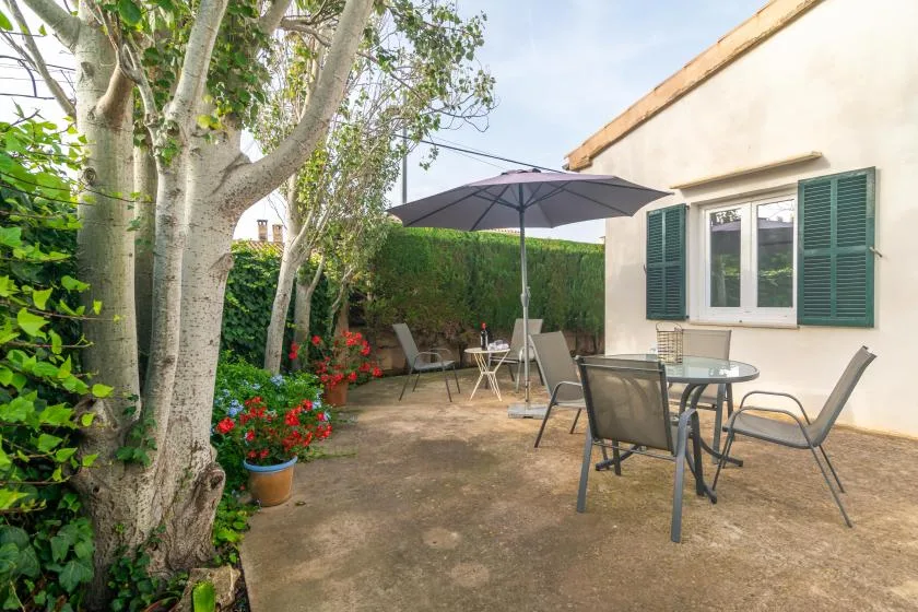 A garden patio with outdoor seating, a large umbrella, and flowering plants.