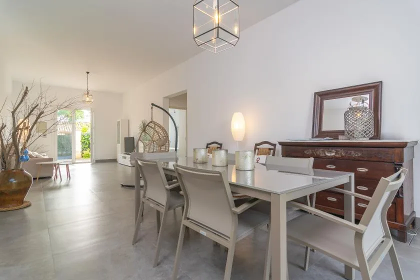 A dining area with a long table and chairs beside a dark wooden sideboard.