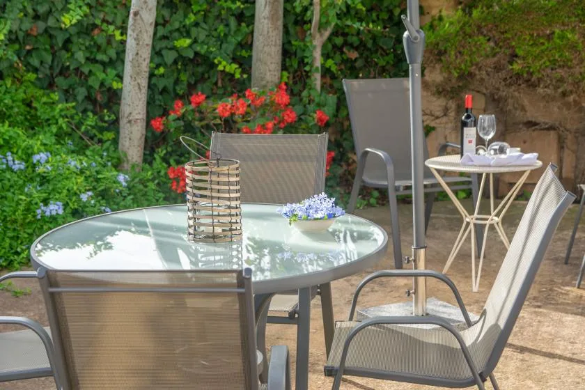 An outdoor patio dining area with seating, tables, and flowering plants.