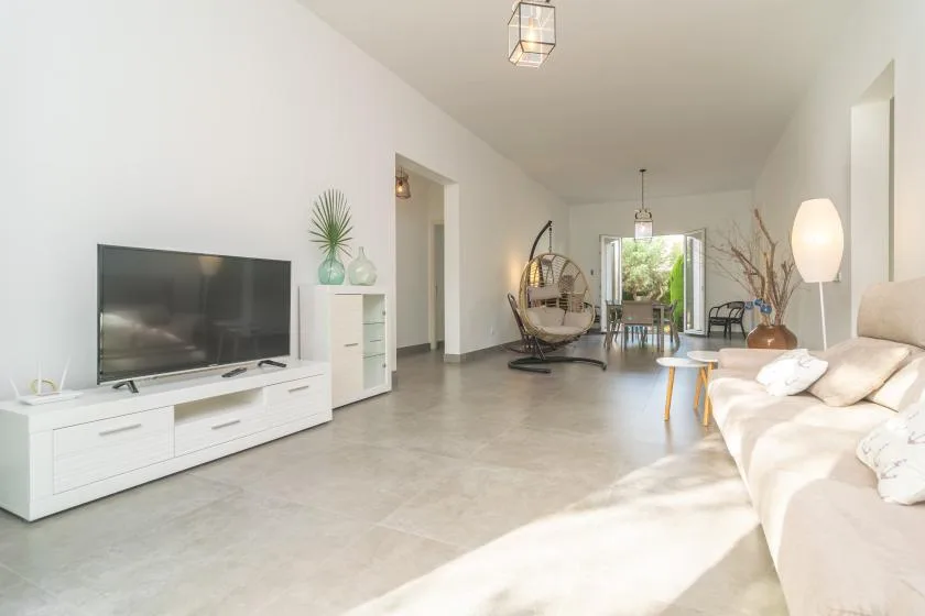 A bright living room with a television, seating, and a hanging chair.