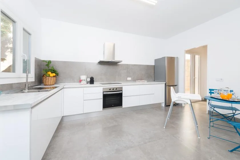 A bright modern kitchen with white cabinets and a dining table.