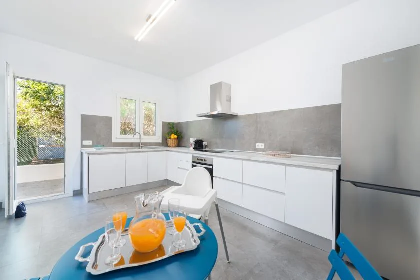 A bright kitchen with white cabinets, a gray backsplash, and a small dining table.