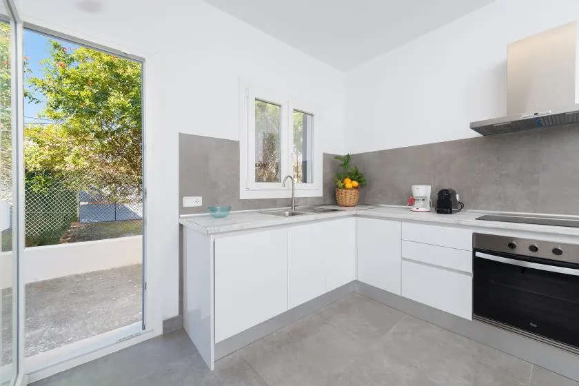 A bright modern kitchen with white cabinets, a countertop, and a window.