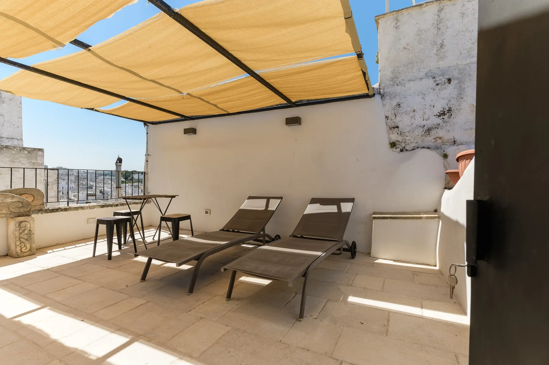 Una terraza soleada en la azotea con asientos de descanso bajo un toldo de tela.