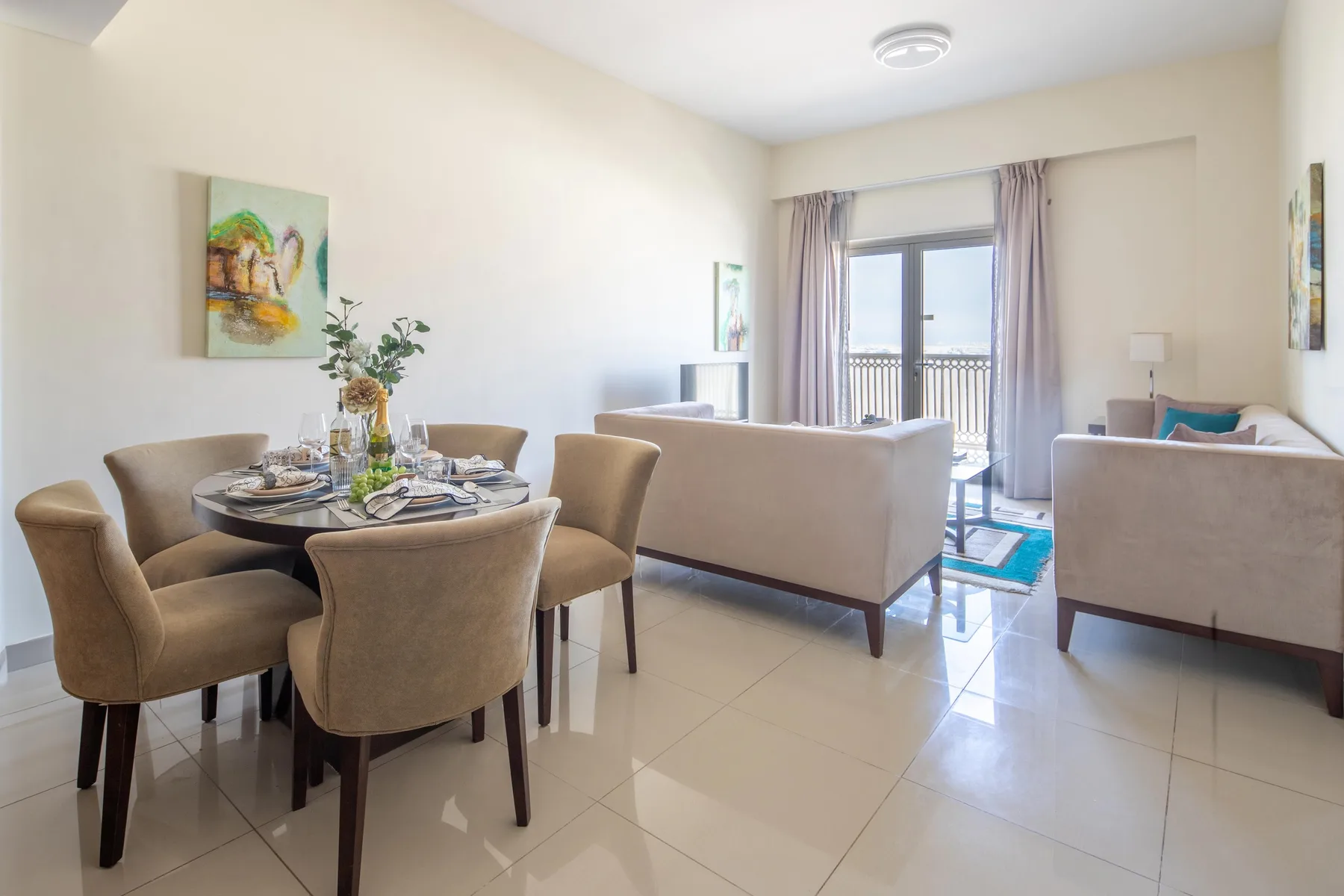 Una luminosa sala de estar y comedor con mesa, asientos y una puerta al balcón.