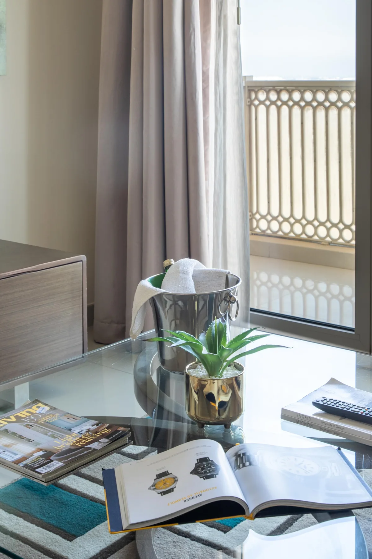 A bright room with a glass table, open books, and a potted plant.